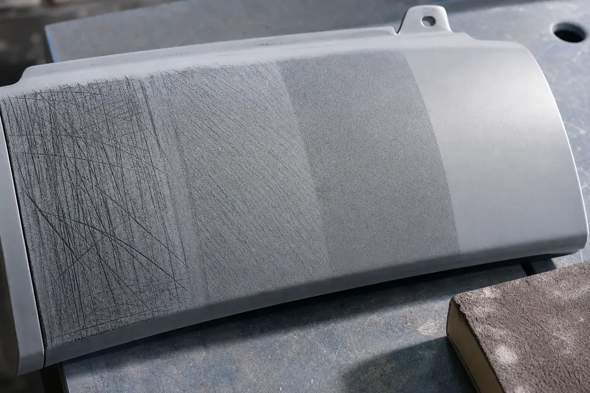 Close-up of guide coat and sanding scratch patterns on automotive primer after different grit steps