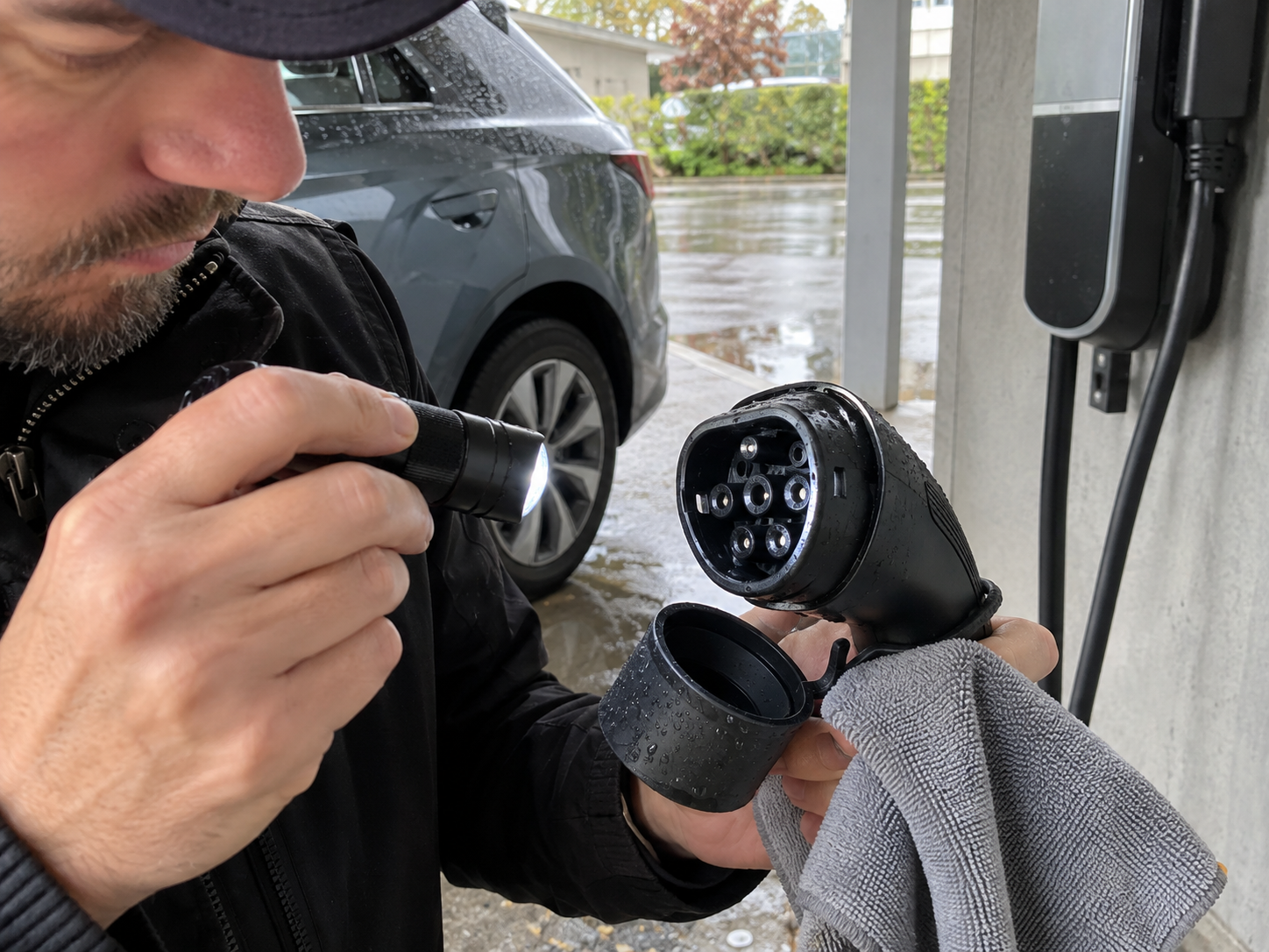 EV Charging Accessory Warning Signs: Heat, Damage, Moisture, and Poor Fit 2 Technician inspecting moisture and contamination around a disconnected EV charging connector and protective cap after rain