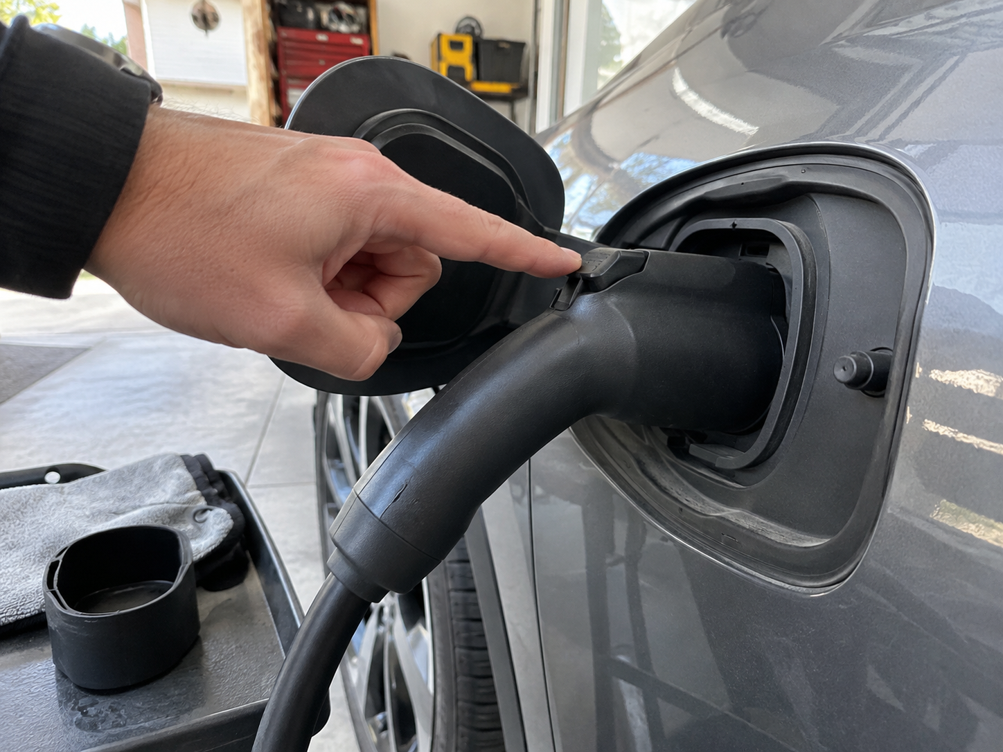 How EV Charging Connector Locking Mechanisms Work 1 Hand pointing to the latch on an EV charging connector seated in a vehicle inlet