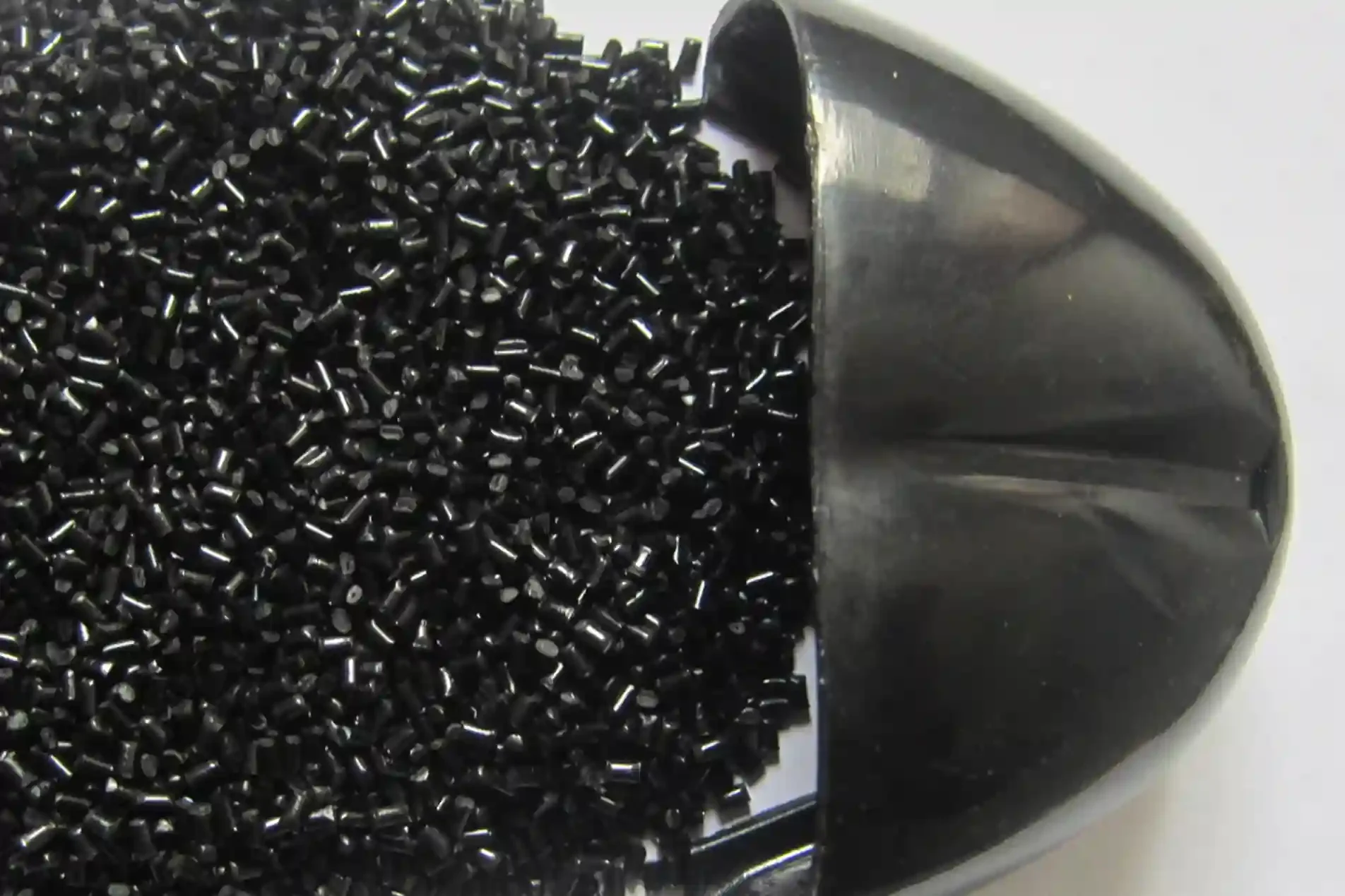 Manufacturing Capabilities 10 Black plastic resin pellets beside a gloss black molded part