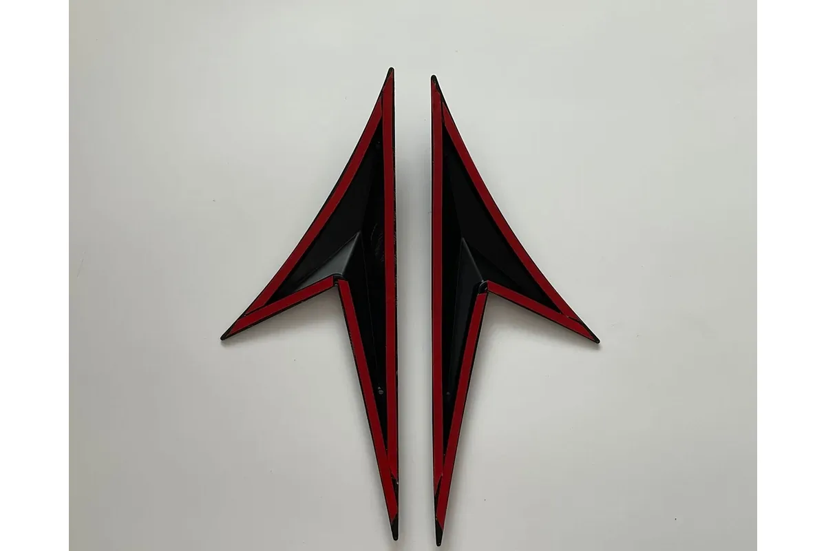 Chrome Delete Guide: Vinyl Wrap vs Painted vs Black Replacement Trim 3 Back side of two black trim pieces showing red-liner adhesive tape along the edges