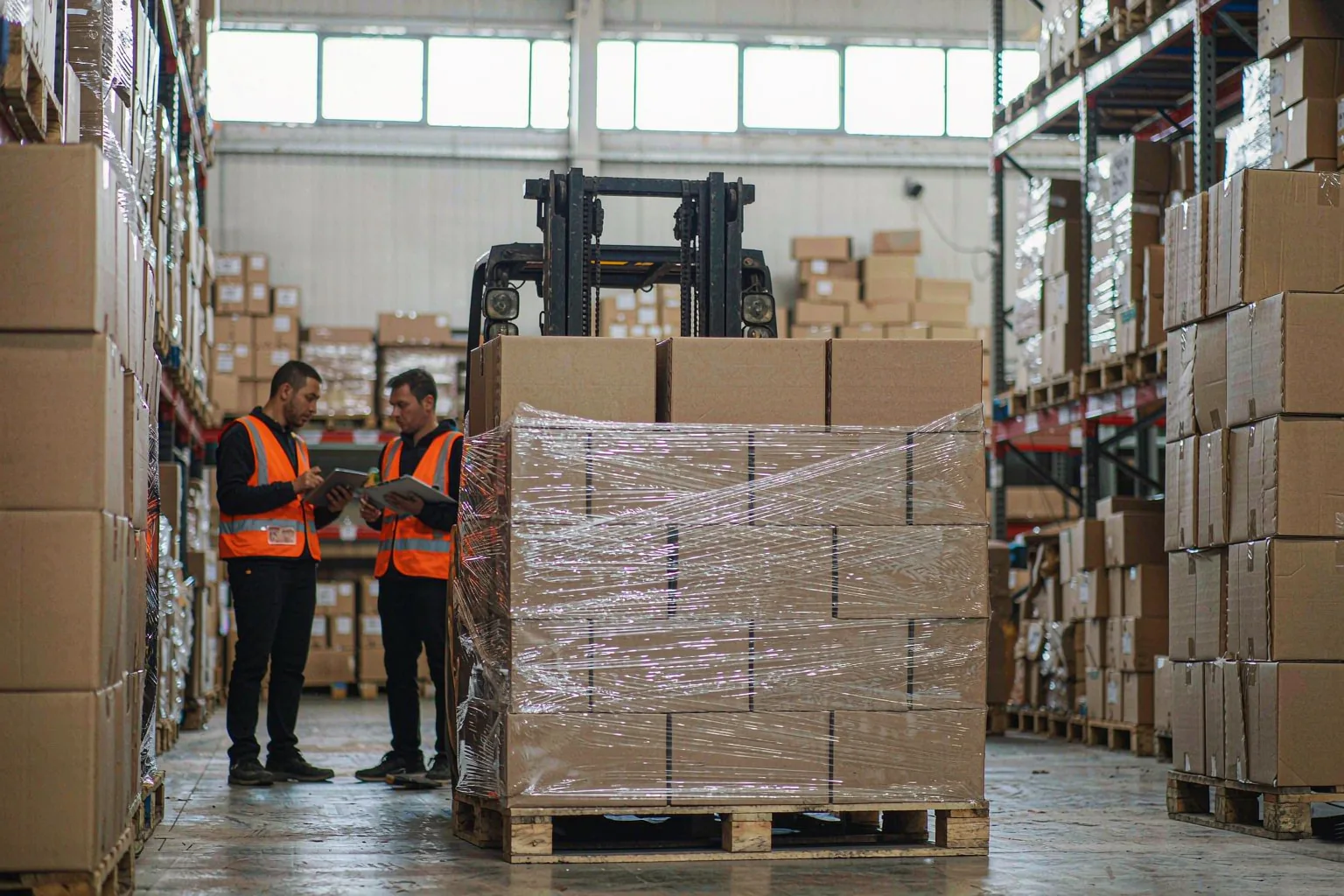Solutions 1 Two warehouse staff checking a wrapped pallet of auto parts cartons