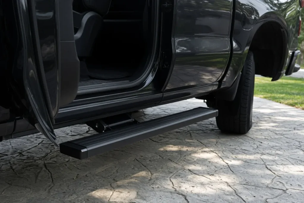 Black aluminum electric running board deployed under the open rear door of a pickup