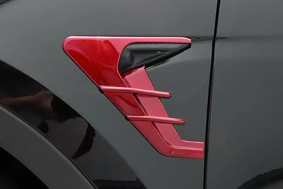 Tesla Model Y Accessories: What Distributors Should Stock and How to Check Fit 1 Red trim piece fitted around the side camera on the front fender of a dark gray car