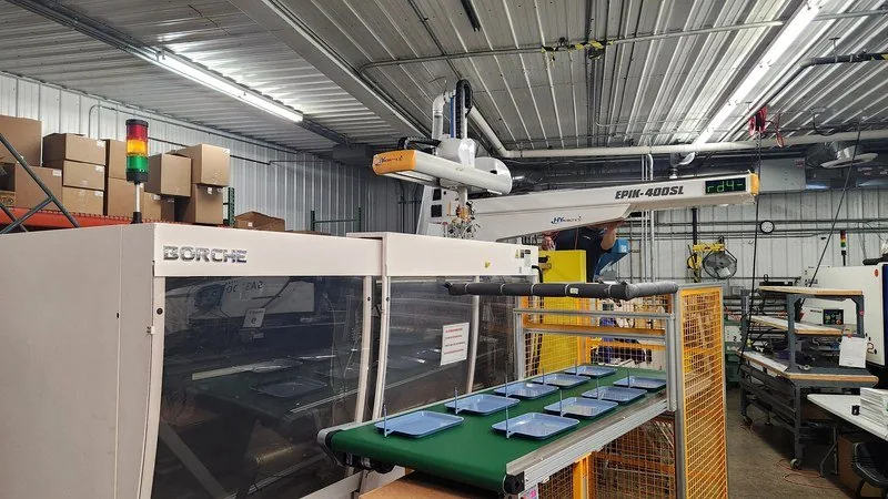 About 12 Injection molding machine with a take-out robot placing molded parts on a conveyor