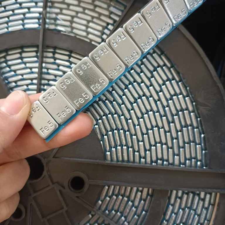 Close-up of 5g steel segments unwinding from an adhesive wheel weight roll