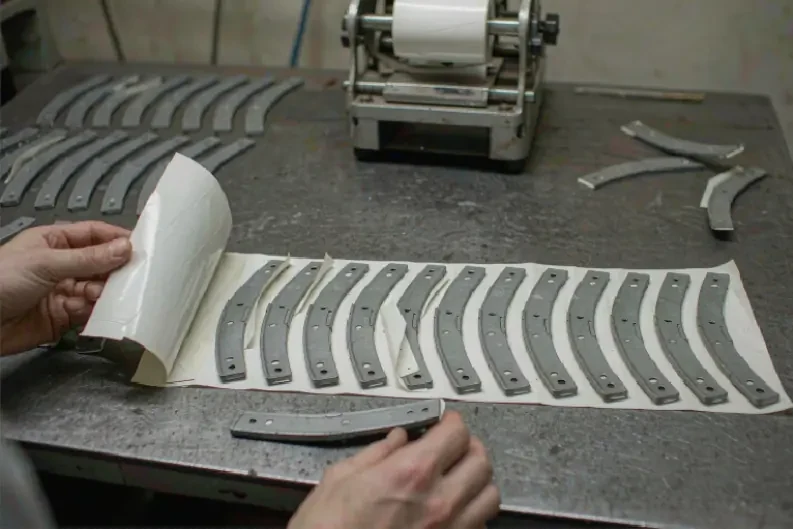 Adhesive wheel balancing weight strips being peeled from backing paper